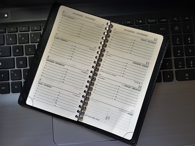 Un agenda papier ouvert posé sur un clavier d'ordinateur